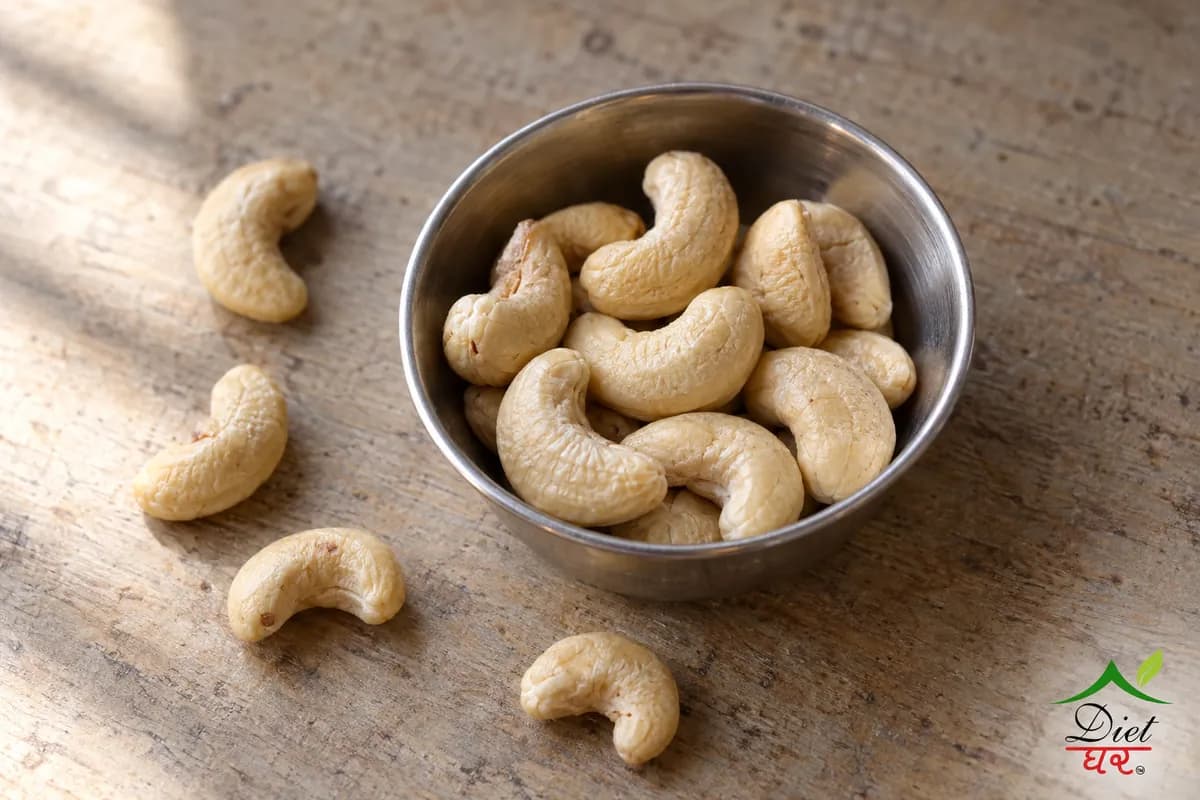 About ten cashew nuts in a small steel katori with a few on the counter