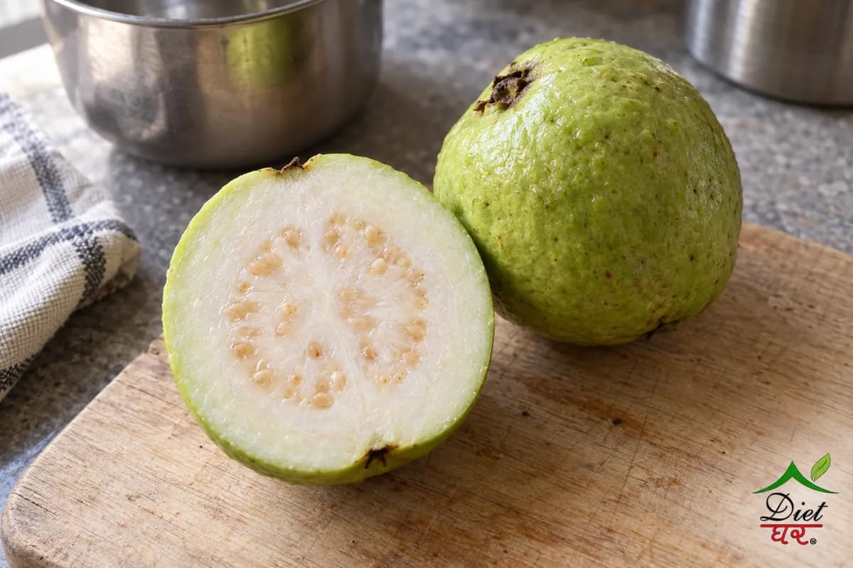 A guava cut in half beside a whole guava