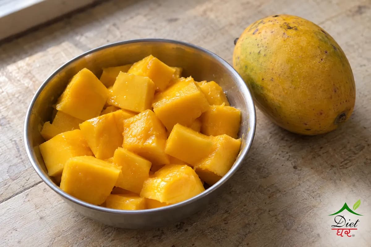Sliced ripe mango in a steel bowl beside a whole mango