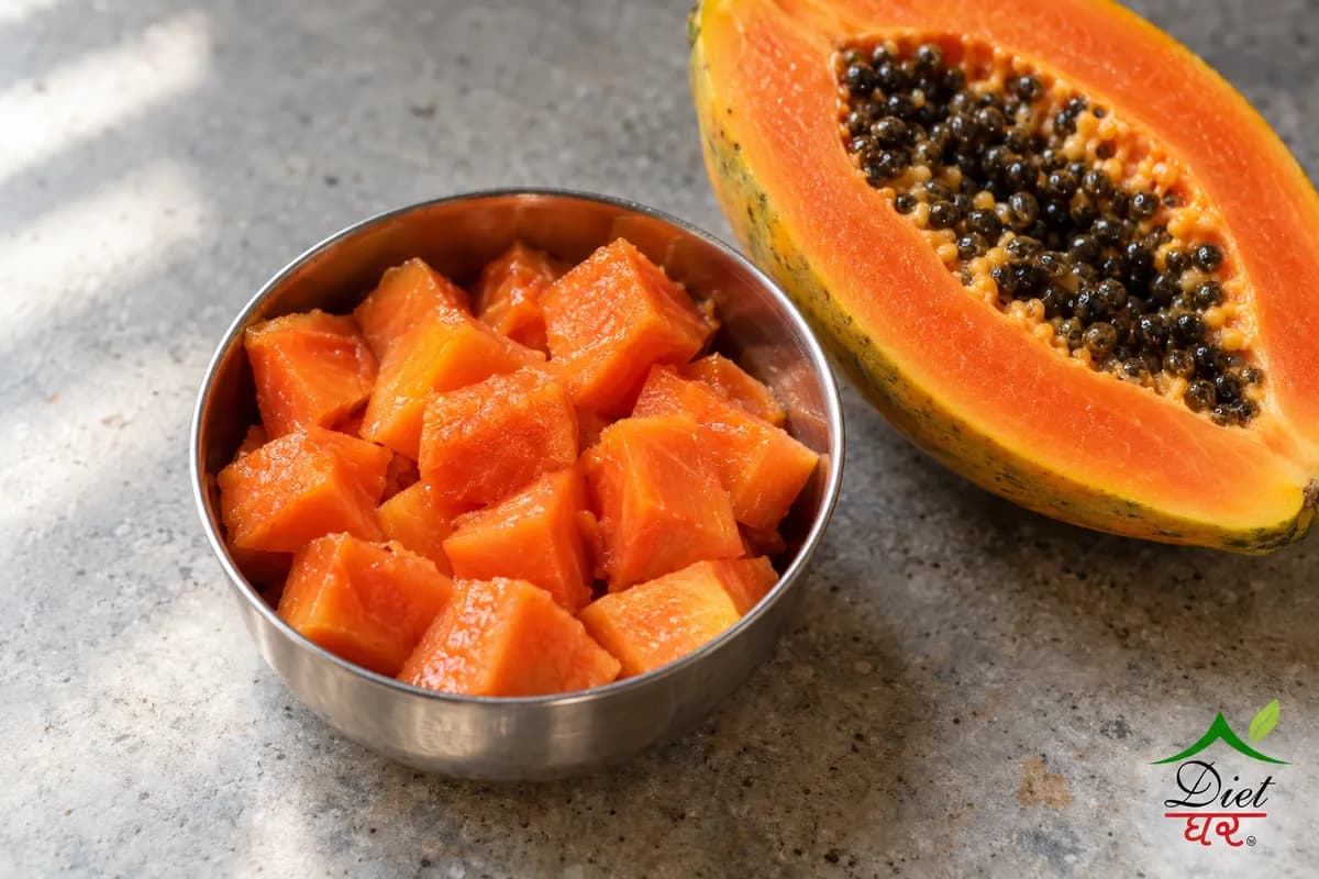 Ripe papaya cubes in a steel katori beside half a papaya