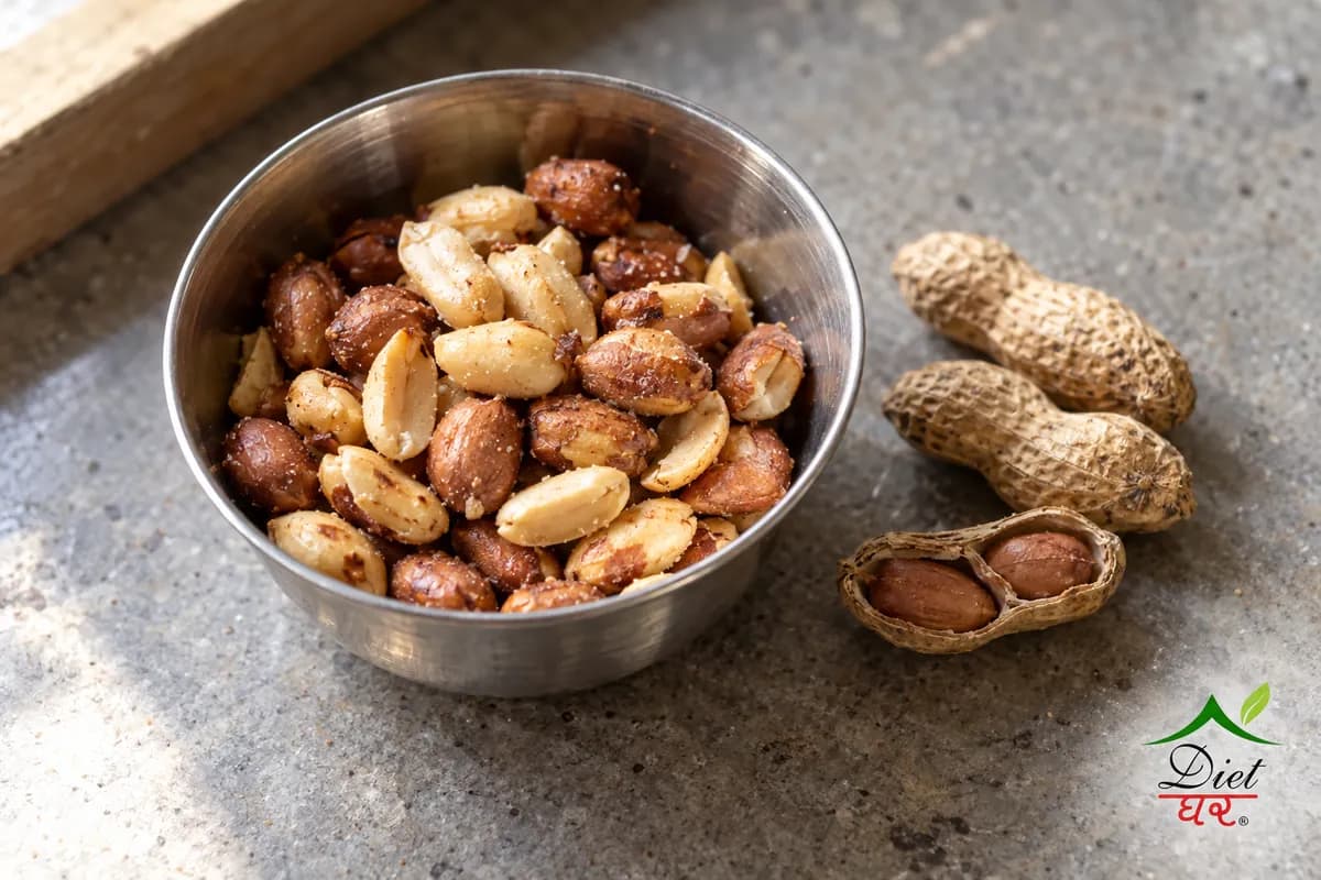 Roasted peanuts in a small steel katori beside peanuts in their shells