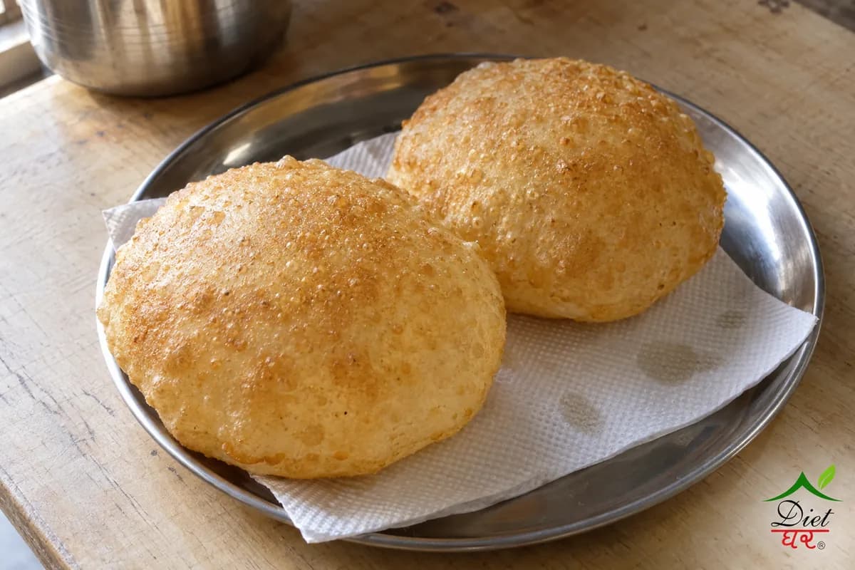 Puri, photographed as two puffed golden puri, in a home kitchen