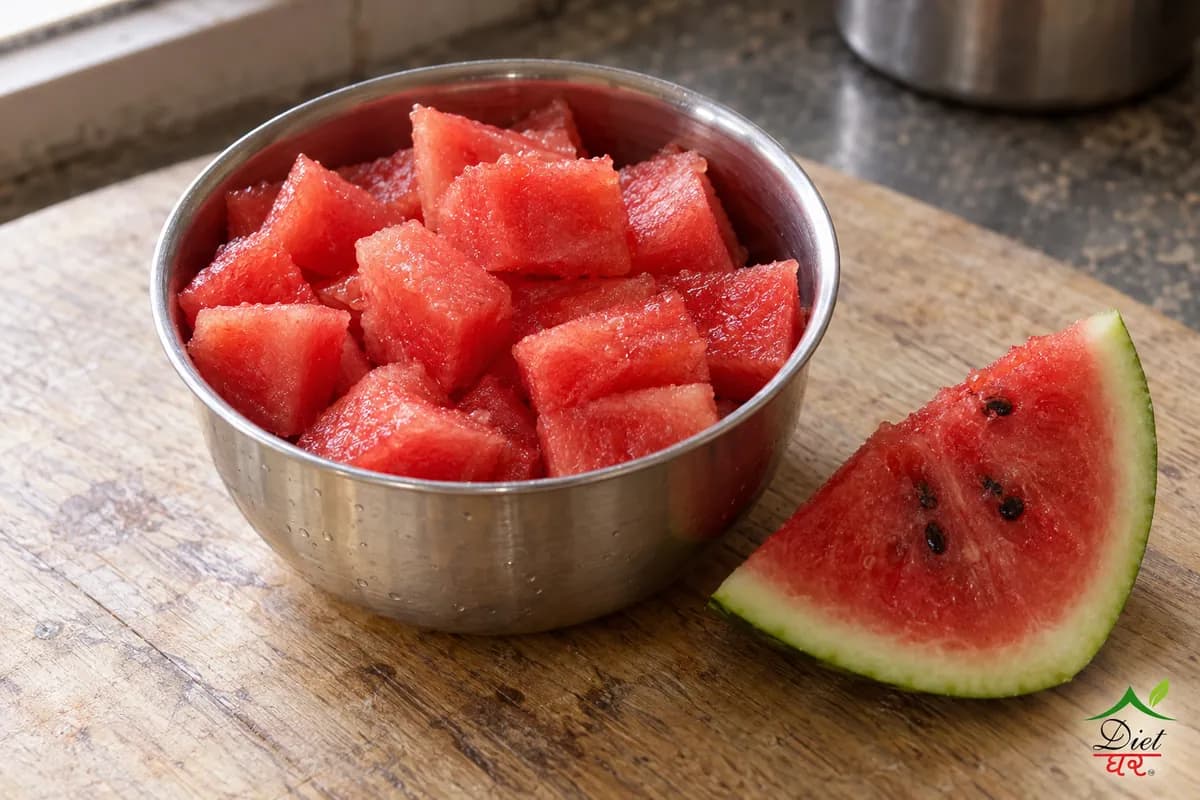 Watermelon cubes in a steel bowl beside a watermelon slice